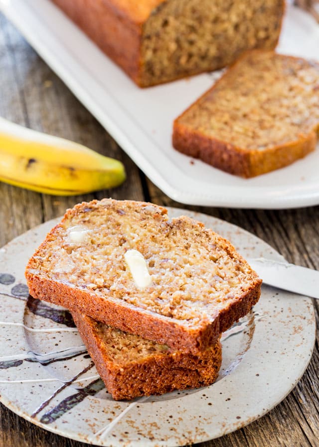 two slices of banana nut bread on a plate with butter