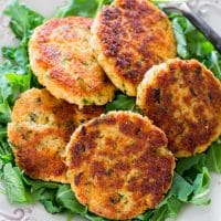 crab cakes sitting on top of a plate full of greens
