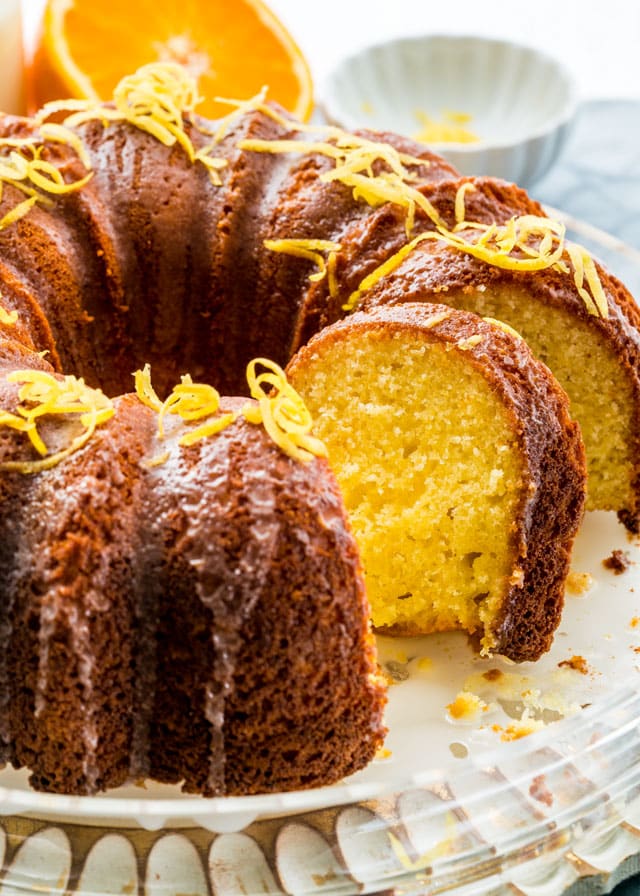 a lemon bundt cake on a platter drizzled in glaze and topped with lemon zest