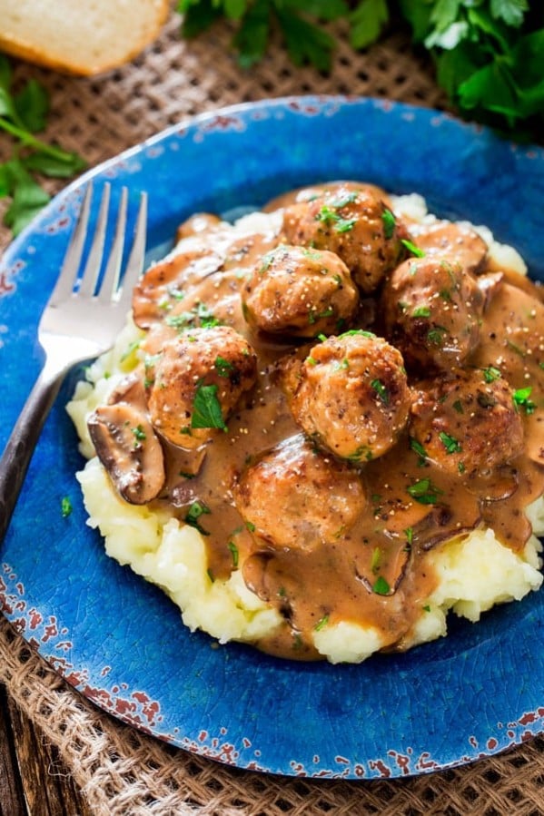 a plate of mashed potatoes topped with meatballs in mushroom sauce