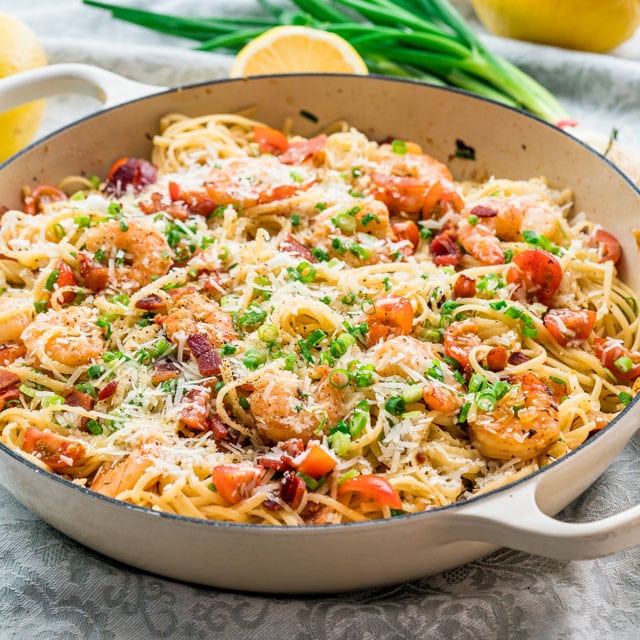 shrimp scampi in a pan topped with bacon and cheese