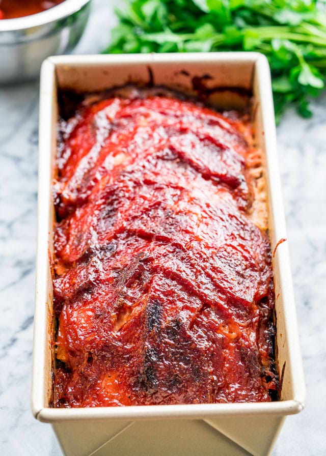 meatloaf in a loaf pan topped with bacon and bbq sauce fresh out of the oven