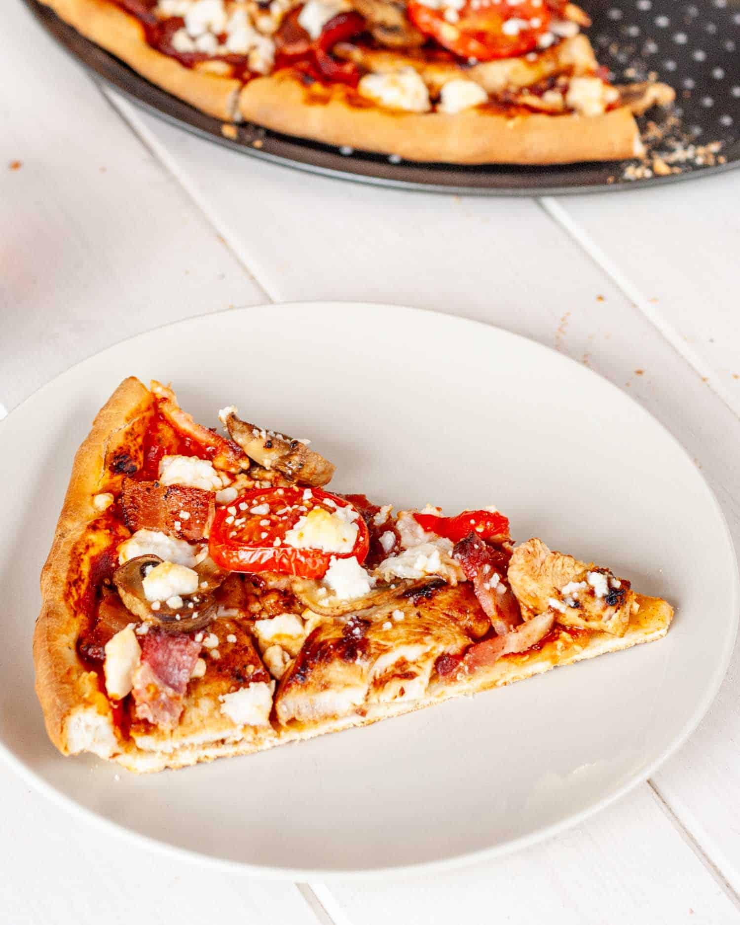 a slice of freshly baked bbq chicken and feta pizza.