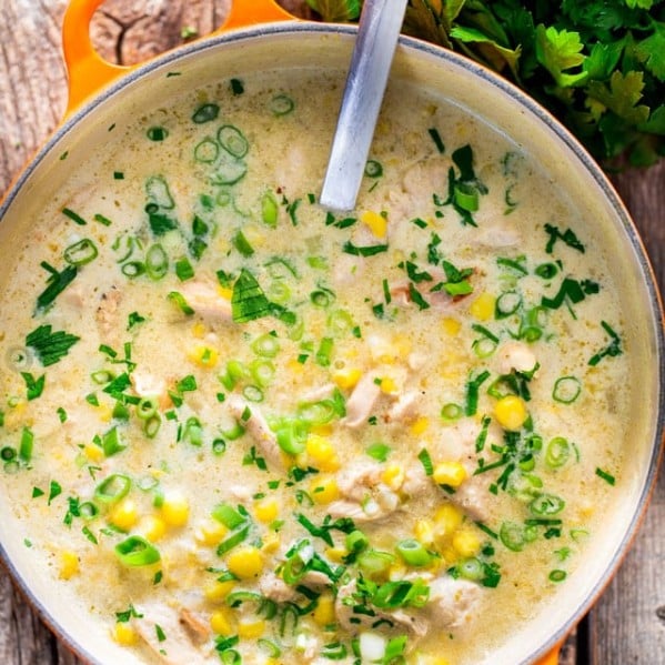 overhead shot of a ladle sitting in a pot full of chicken and corn chowder