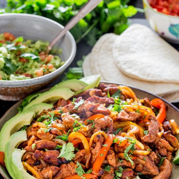 a plate full of the pork fajita filling garnished with sliced avocado