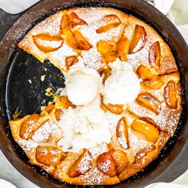 overhead shot of apricot clafoutis in a black skillet with a couple scoops of ice cream on it