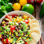 overhead shot of a bowl of black bean corn avocado salad garnished with tortilla chips