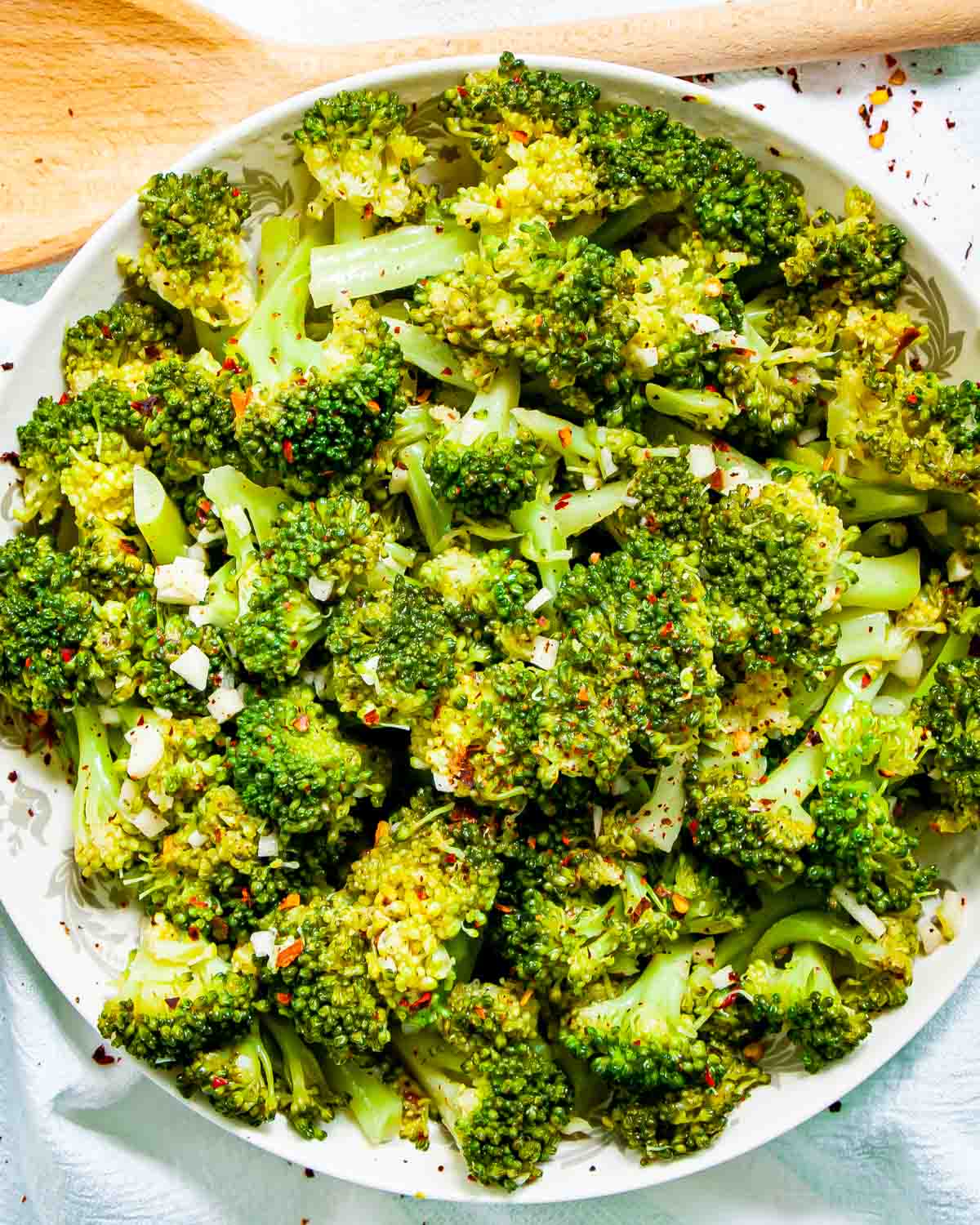 overhead shot of broccoli salad in a white plate garnished with red pepper flakes