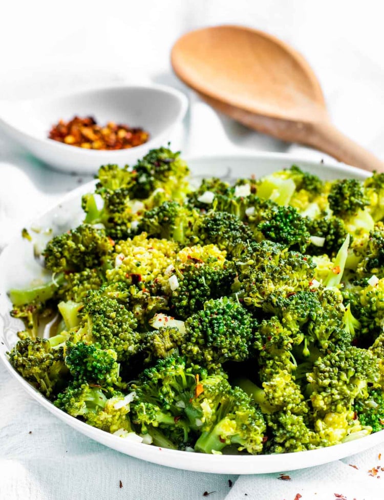 side view shot of broccoli salad in a white bowl with a wooden spoon in the background