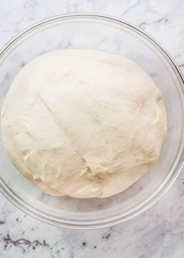 pizza dough rising in a bowl
