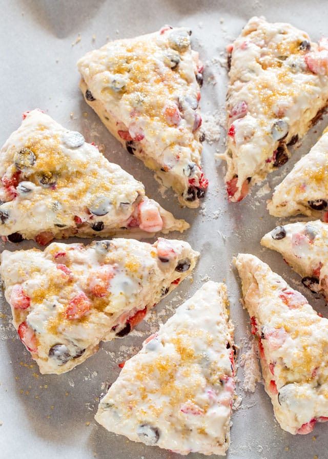 raw strawberry chocolate chip scones cut and on a baking sheet 