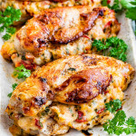 side view shot of 3 stuffed chicken breasts with roasted peppers and asiago cheese on a serving platter and garnished with parsley