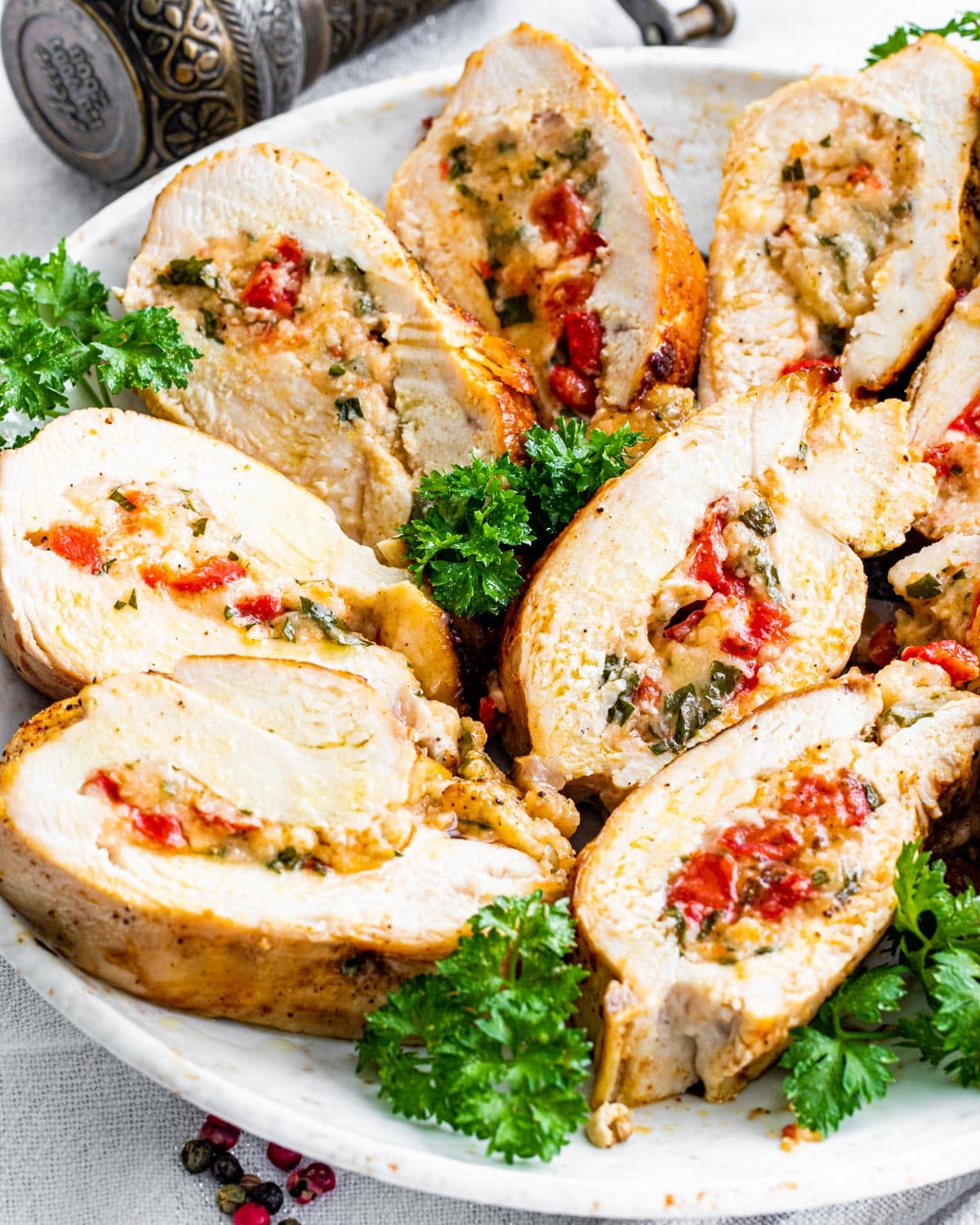side view shot of sliced up stuffed chicken breasts on a serving platter garnished with parsley