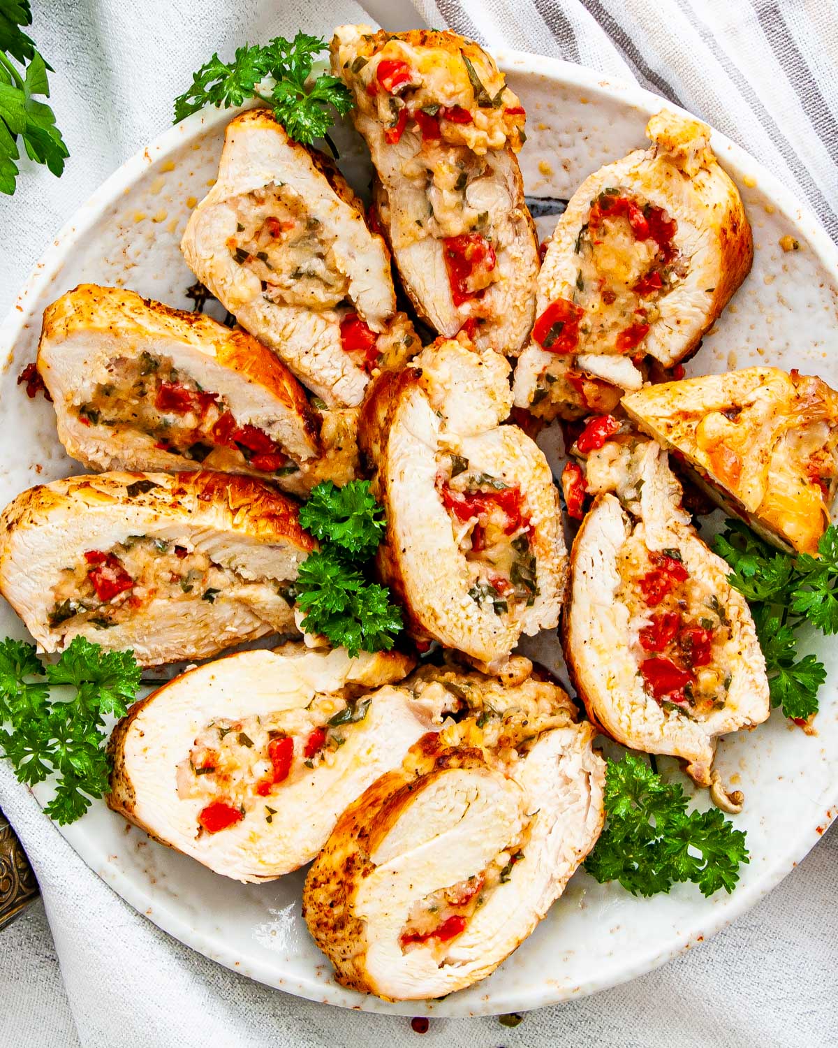 overhead shot of sliced up stuffed chicken breasts on a serving platter garnished with parsley