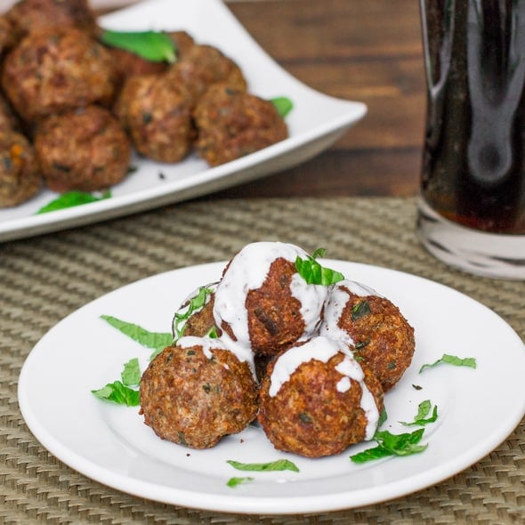 baked lamb meatballs on a plate covered in sauce 