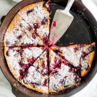 overhead shot of cherry clafoutis in a pan with two slices missing and a pie lifter in the empty space
