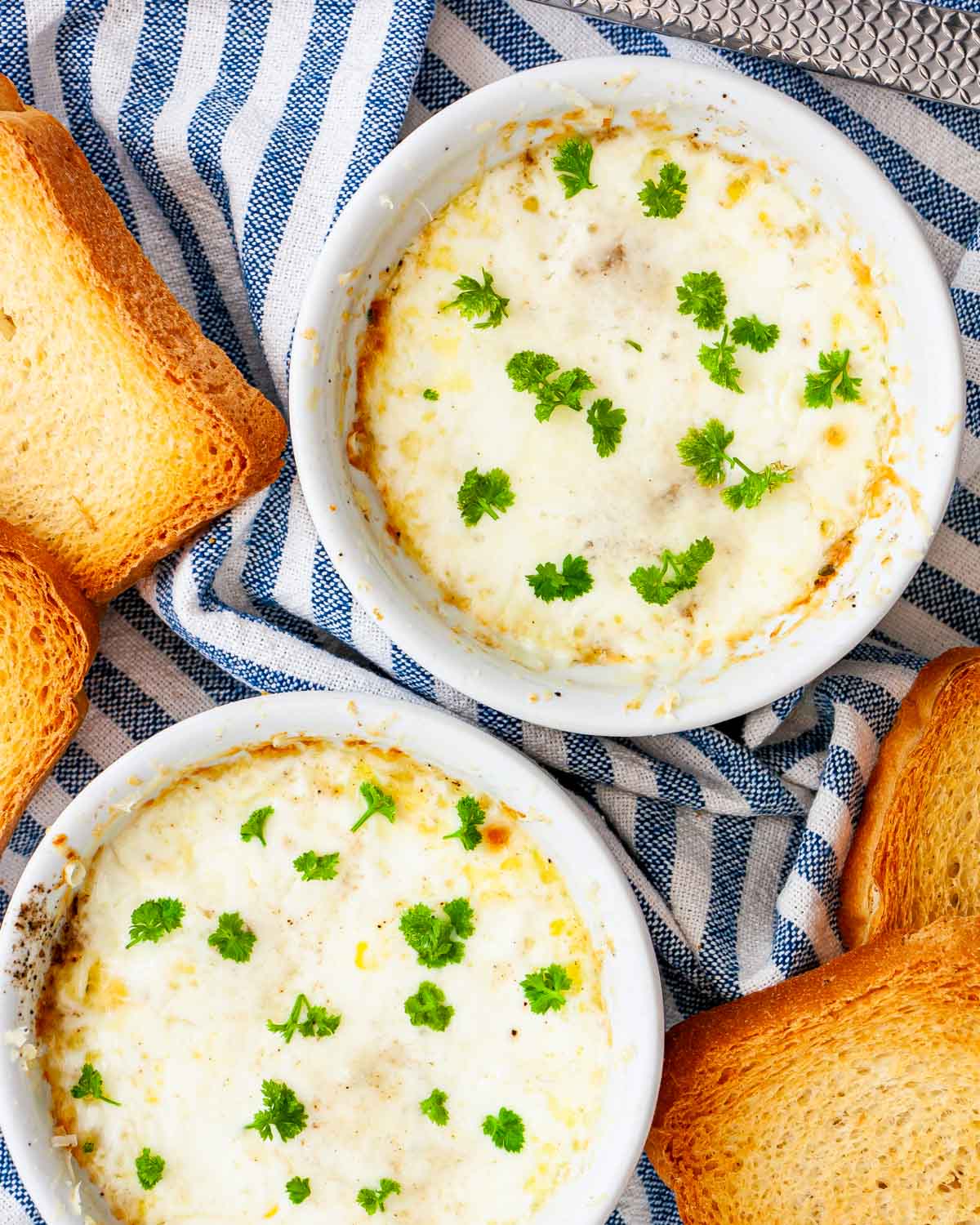 overhead of 2 ramekins with creamy baked eggs and garnished with parsley