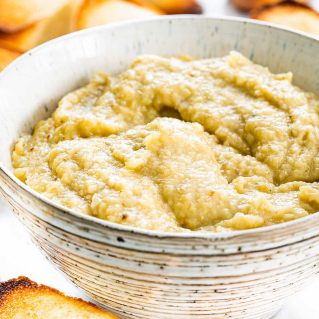 side view shot of a bowl of eggplant dip surrounded by toasted bread