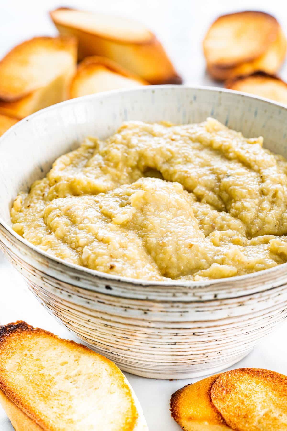 eggplant dip in a bowl surrounded by toasted bread