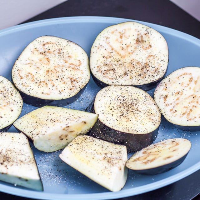 Sliced eggplant on a plate sprinkled with salt and pepper