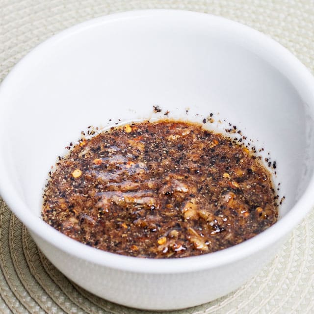 Mixture of garlic paste, rice vinegar, soy sauce, sesame oil, salt, pepper and red chili flakes mixed in a bowl