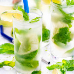 mojito cocktails in tall glasses with mint, limes and straws