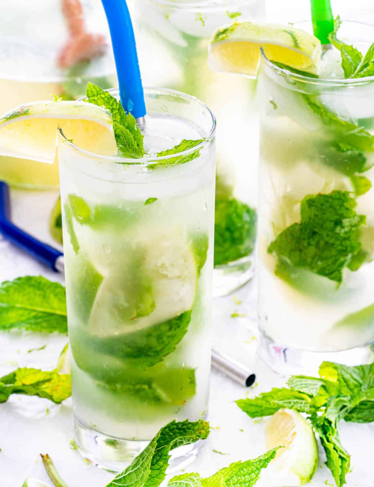 mojito cocktails in tall glasses with mint, limes and straws