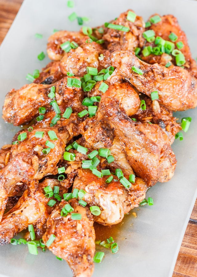 top shot of finished wings on a plate, garnished with chopped green onions