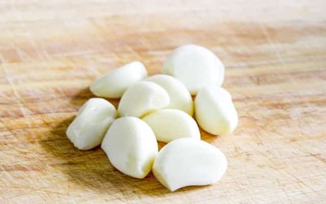 9 cloves of garlic on a cutting board
