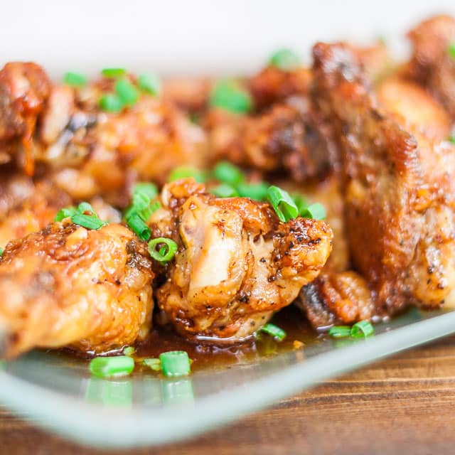 Close up shot of spicy baked chicken wings garnished with chopped green onion