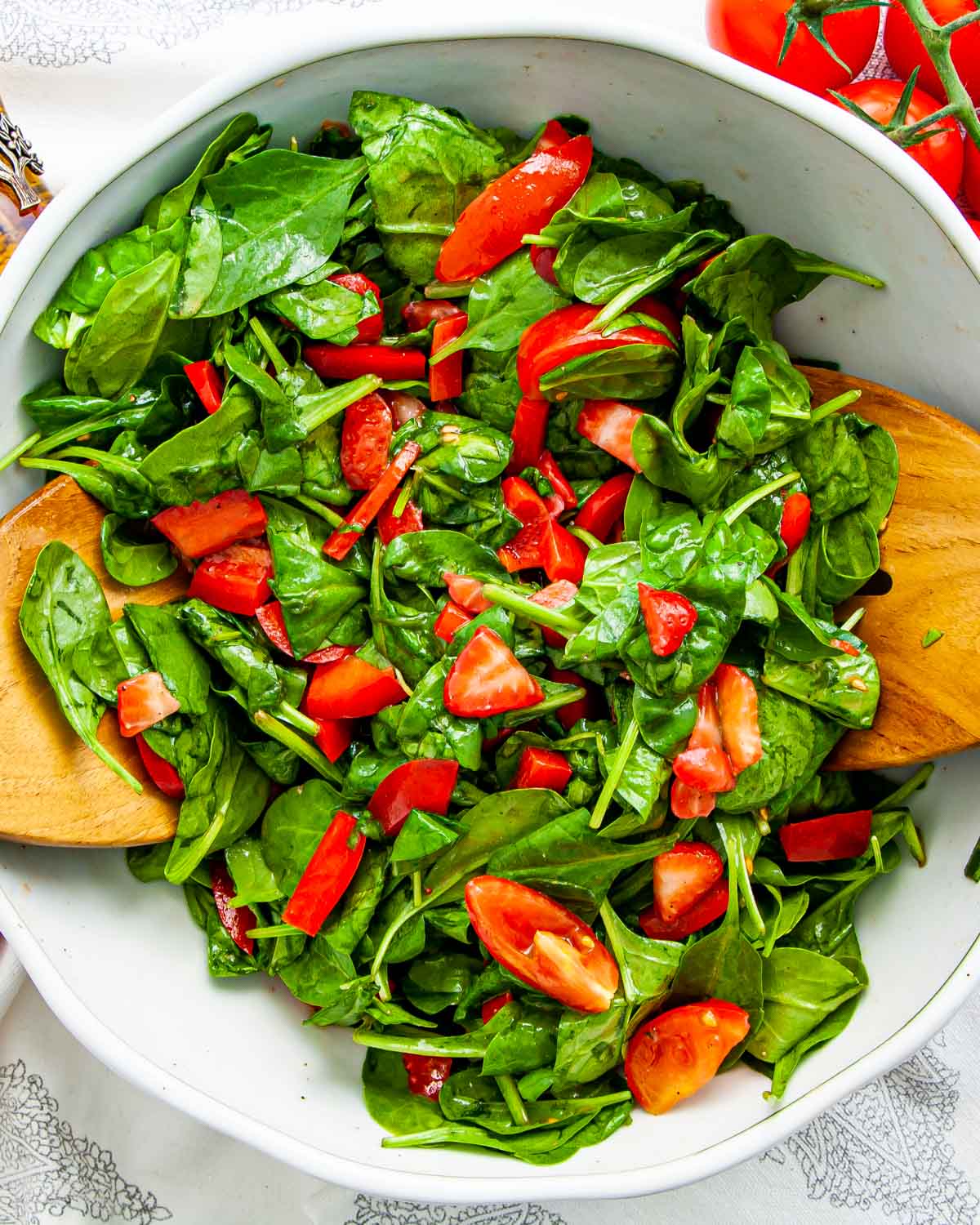 overhead shot of strawberry spinach salad in a white bowl.