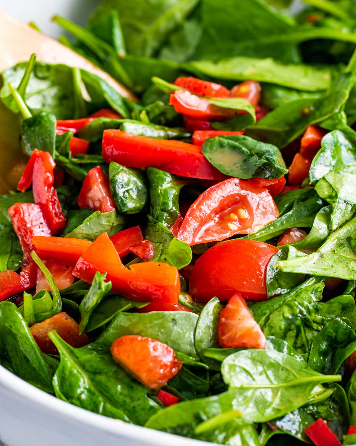 closeup of strawberry spinach salad in a white bowl.