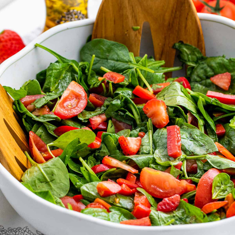 strawberry spinach salad in a white bowl.