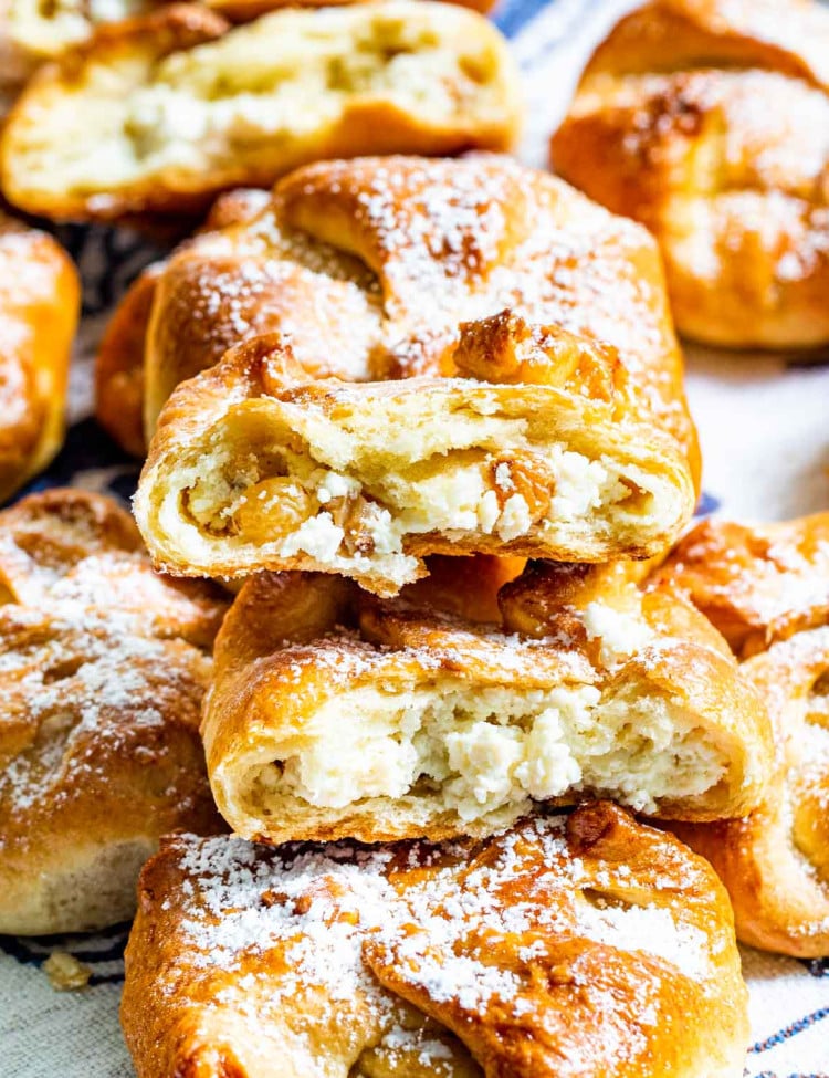 sweet cheese buns stacked on top of each other with the top one broken in half.