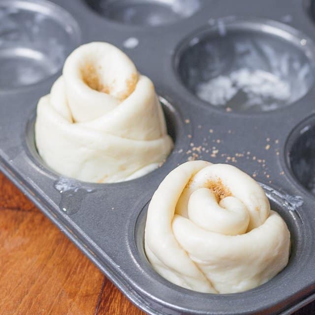 Assembled cinnamon roses placed in a greased muffin tin.