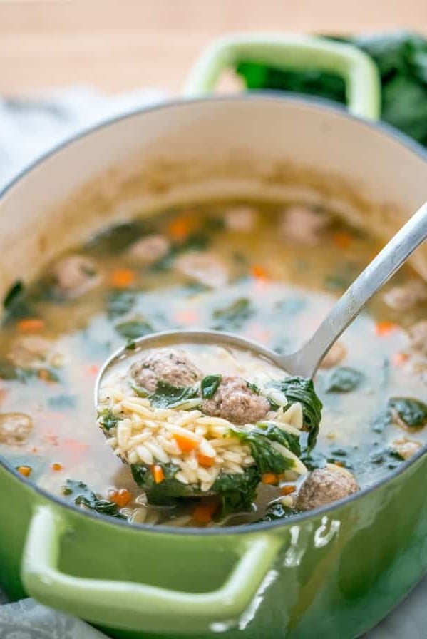 side view shot of a ladle taking a scoop of italian wedding soup