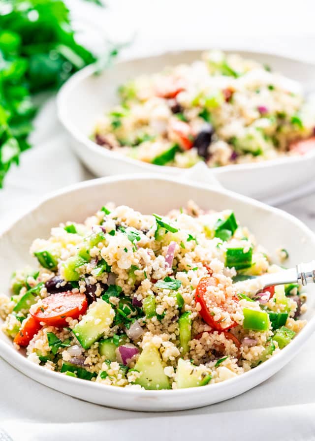 two bowls of Mediterranean Couscous Salad with parsley in the background