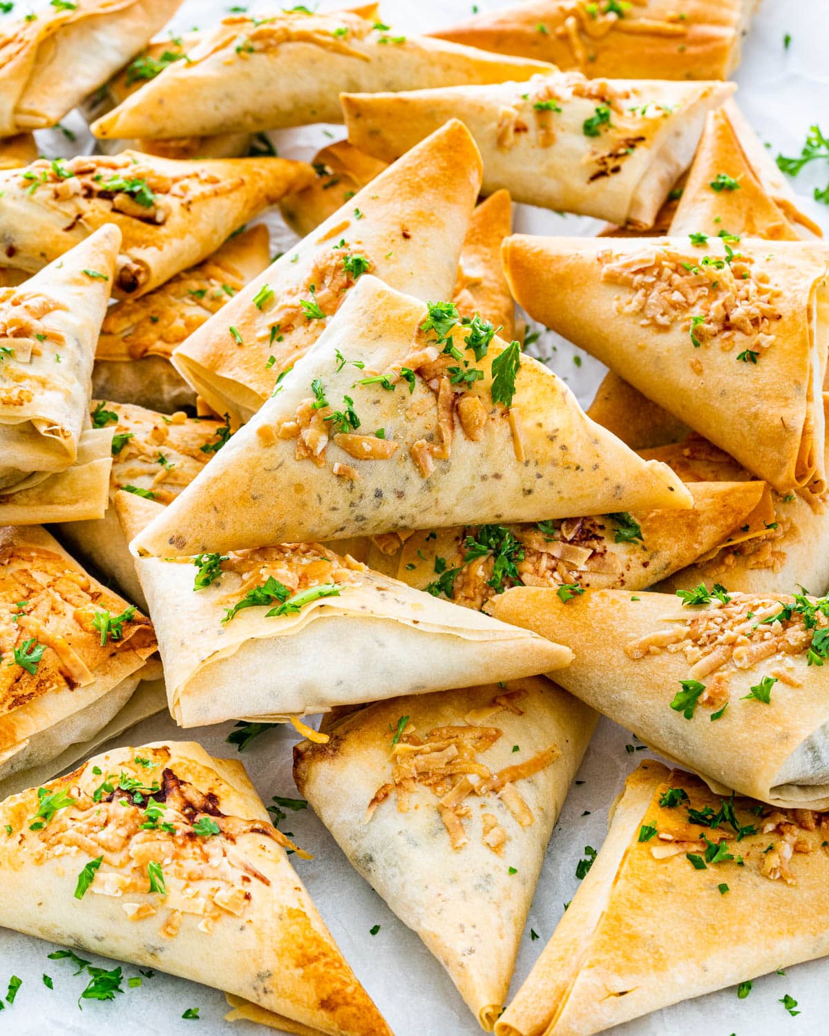 a bunch of spanakopita triangles on parchment paper