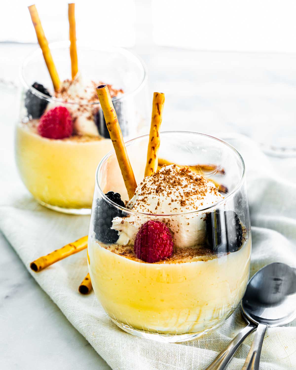 vanilla pudding in a glass topped with fresh berries and whipped cream