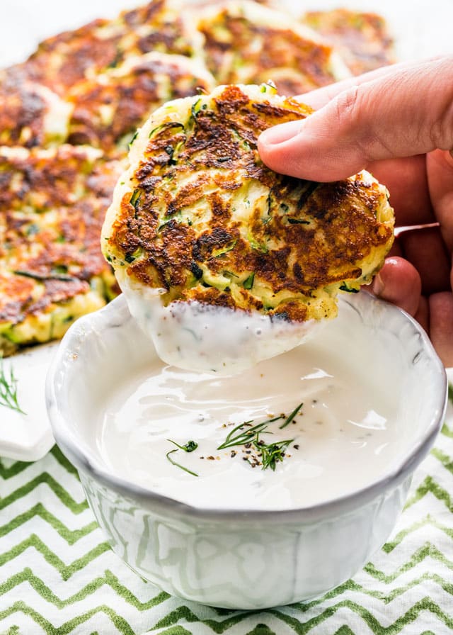 dipping a zucchini patty into ranch dressing
