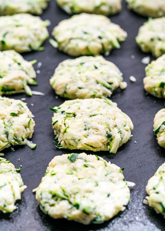 uncooked zucchini patties lined up on a baking sheet