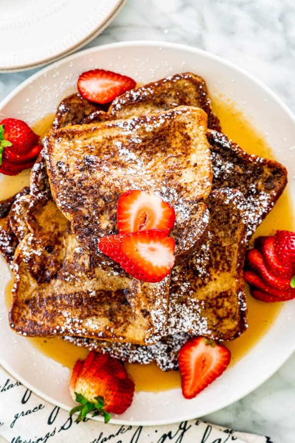 overhead shot of french toast on a plate topped with maple syrup and strawberries