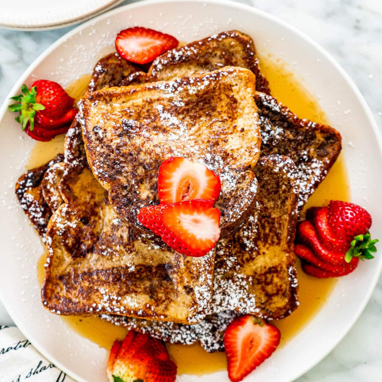 overhead shot of french toast on a plate topped with maple syrup and strawberries