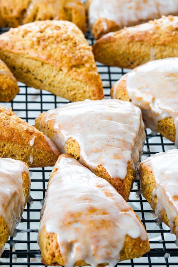 closeup of pumpkin scones on a cooling rack some with glaze on them.