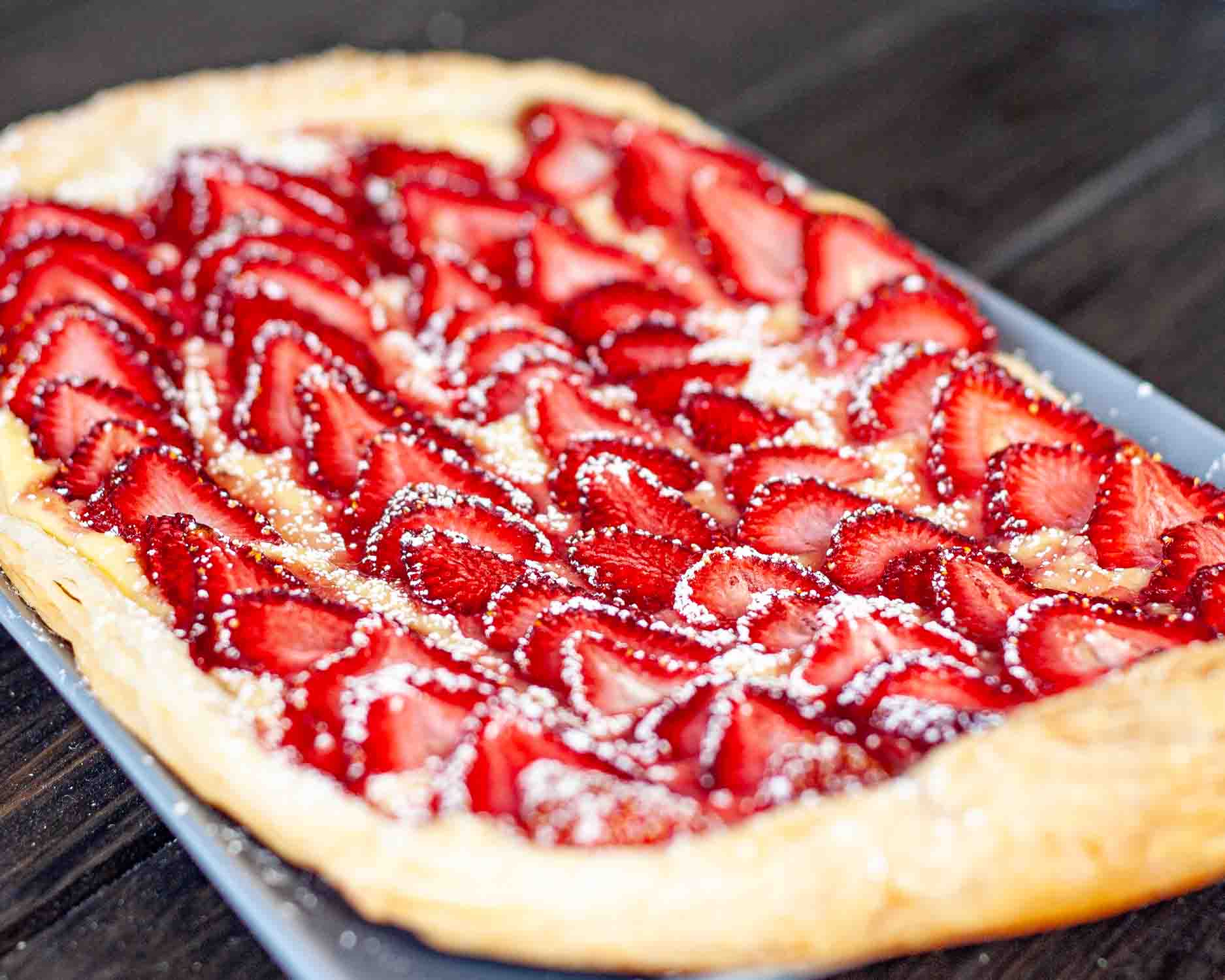 a beautiful strawberry tart on a blue plate.
