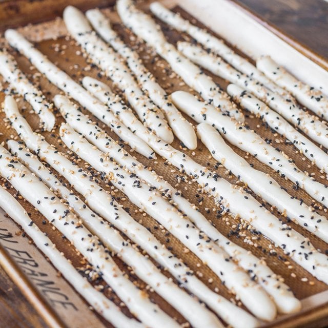 uncooked breadsticks sprinkled with poppy seeds and sesame seeds