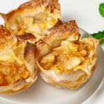 3 mini apple pies in wonton wrappers on a glass plate.