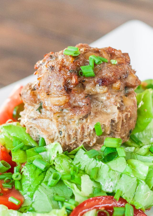 Close up shot of Turkey Meatloaf Muffin on a bed of lettuce with sliced tomatoes and green onions
