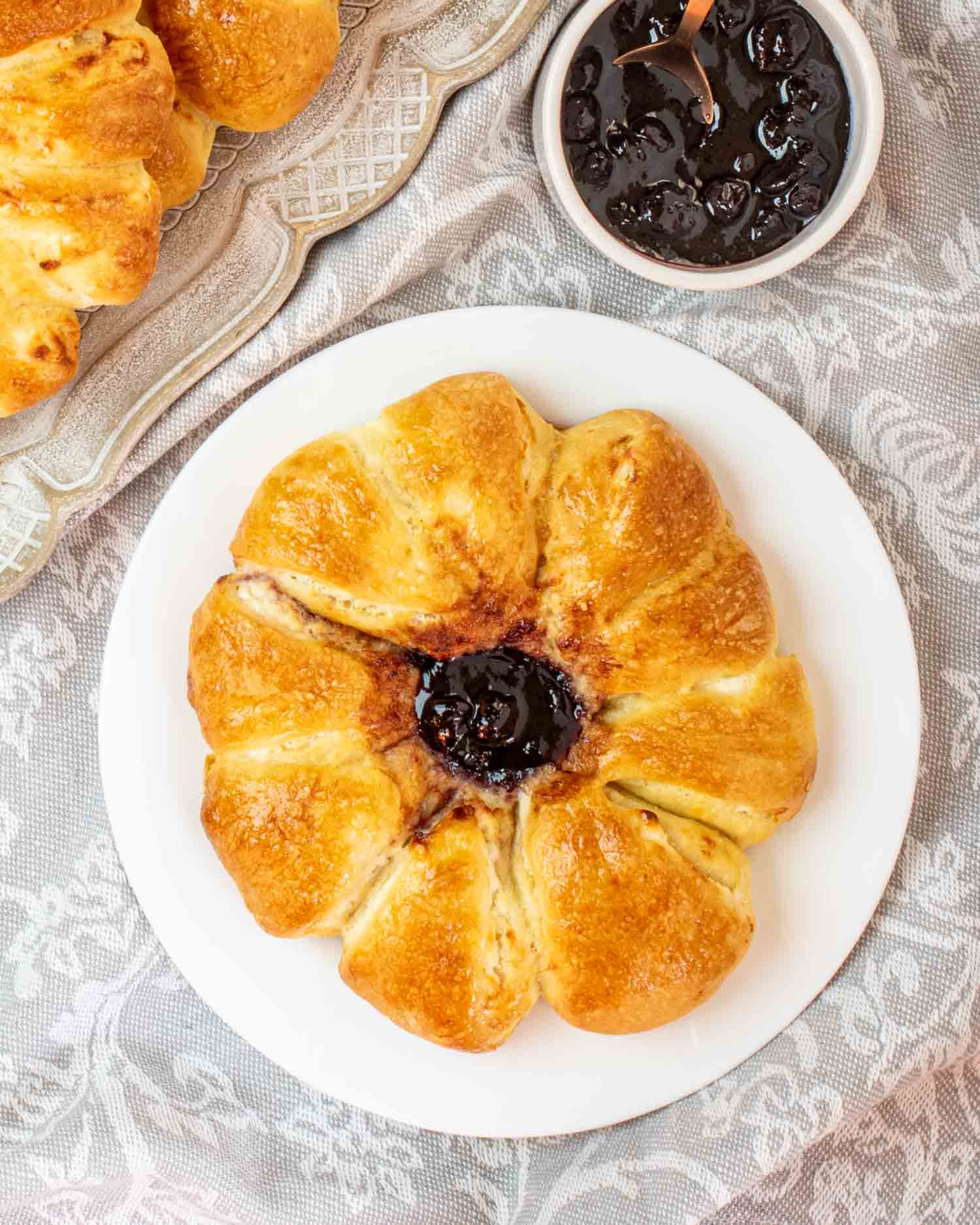 a cheese danish with blueberry jam on a white plate.