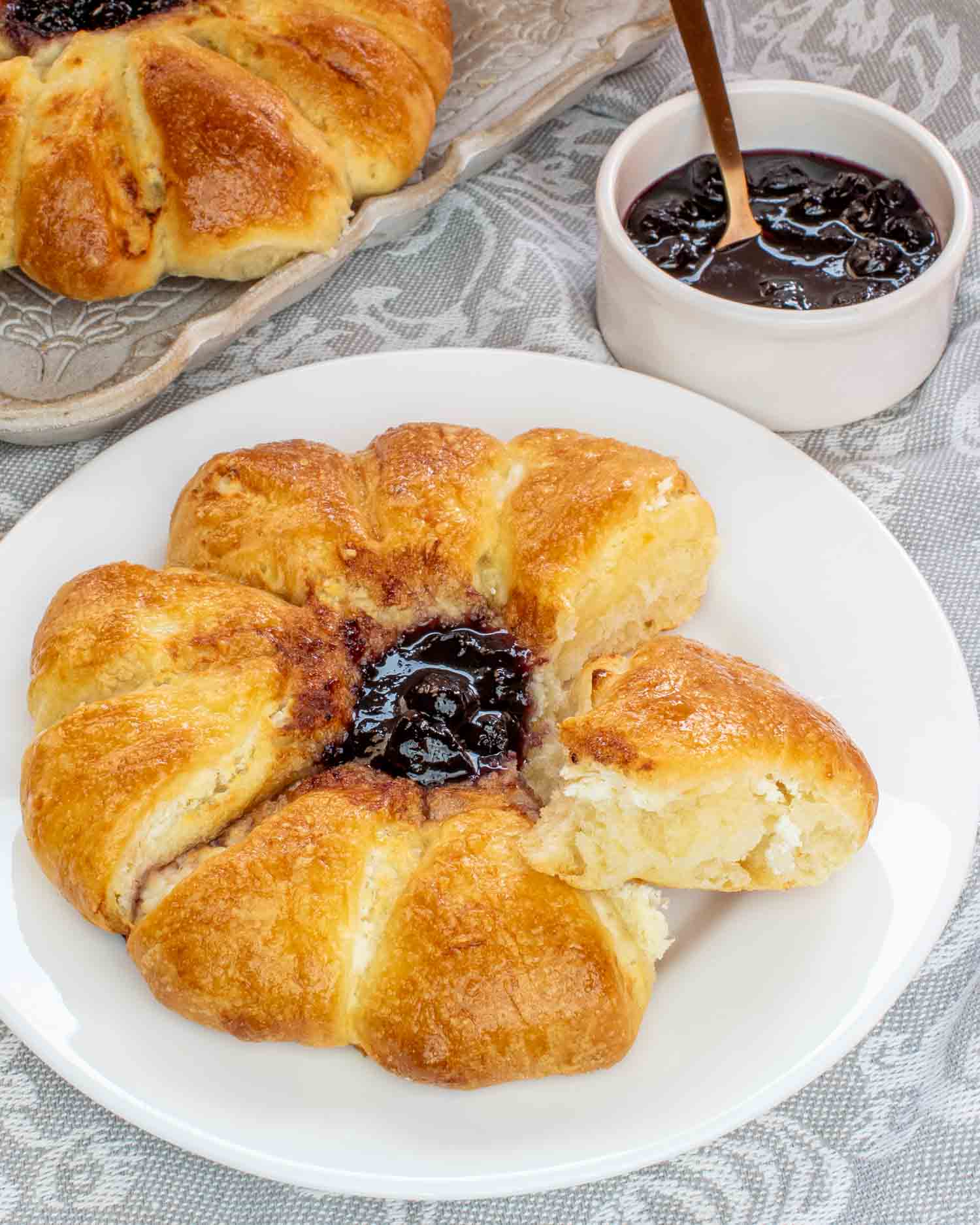 a cheese danish with blueberry jam on a white plate.